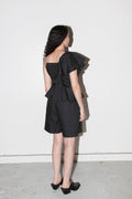 Woman wearing a black outfit with ruffled details against a white background