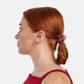 Woman with red hair styled in a braid with a plaid scrunchie on a white background