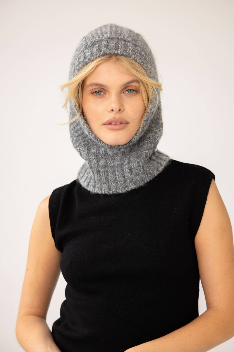 Woman wearing a gray knitted balaclava against a white background