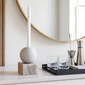 Decorative setup with a candle, glass containers, and a mirror on a shelf.