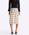 Person wearing a black top and white polka dot skirt on a white background