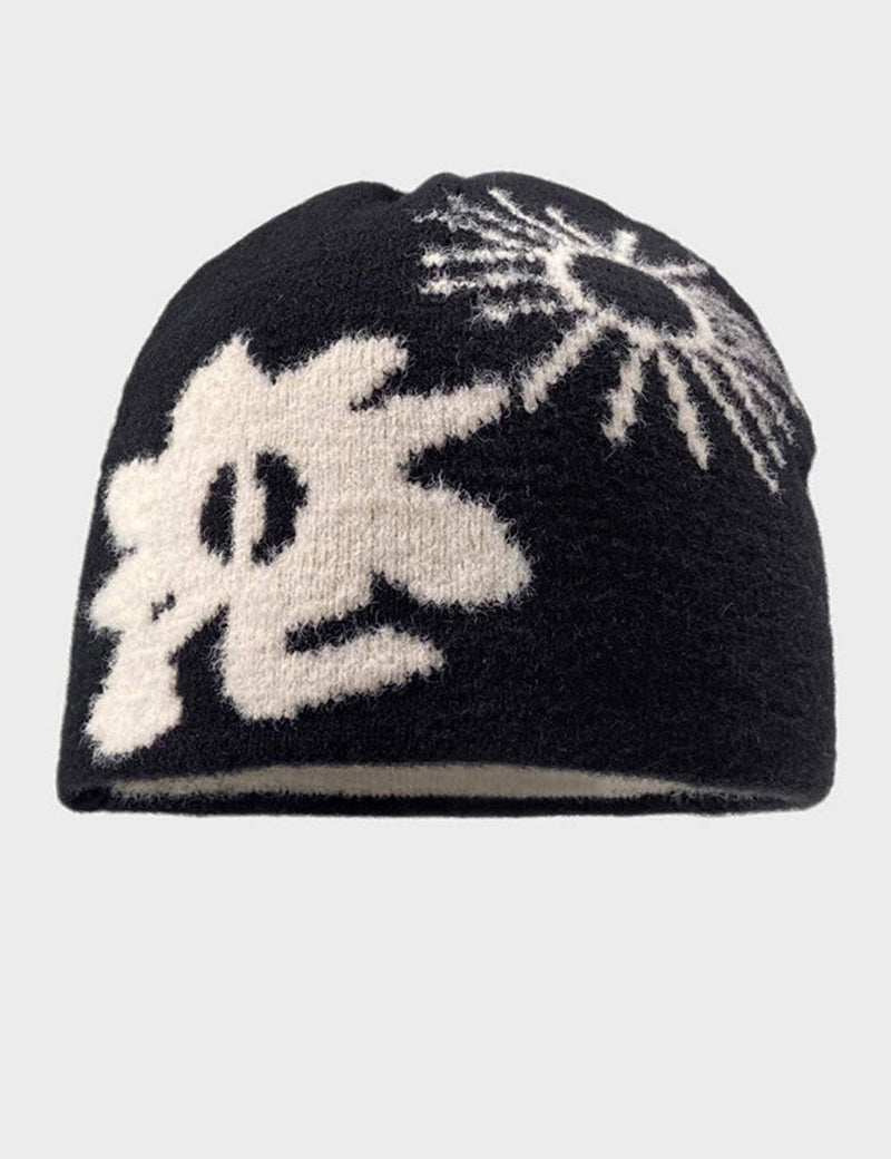 Black beanie with white floral pattern on a light gray background
