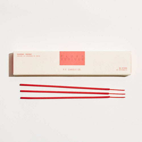Red incense sticks in front of a white box with red label on a white background