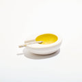 White ceramic dish with yellow interior on a white background