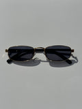 Black sunglasses with gold frames on a light gray background