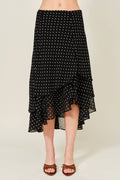 Black polka dot skirt worn by a person on a beige background