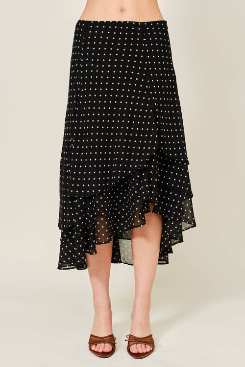 Black polka dot skirt worn by a person on a beige background