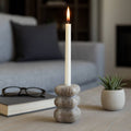 Candle in a stone holder on a coffee table with a book and glasses in the background