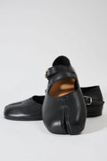 Black leather shoes with buckles on a light gray background