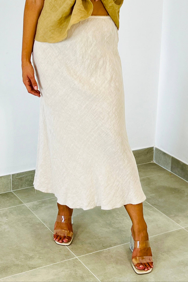 Person wearing a white lace skirt and transparent heels in a minimal indoor setting