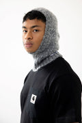 Person wearing a gray hooded garment over a black Carhartt shirt on a white background