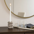 Candle in a stone holder on a table with a mirror in the background