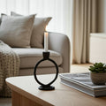 Candle in a black holder on a table with a blurred living room background