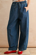 Blue wide-leg jeans worn by a person on a beige background