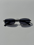 Black sunglasses with thin metal frame on a light gray background
