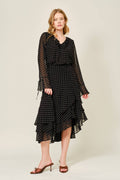 Woman wearing a black polka dot dress with sheer sleeves on a white background