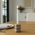 Candle in a stone holder on a wooden table with a blurred background