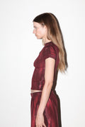 Woman wearing a maroon outfit against a white background