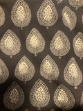 A close-up of a dark brown or charcoal fabric with a repeating metallic gold leaf block-print pattern.