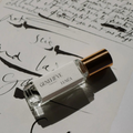 Perfume bottle labeled 'Geneve' on a sheet of music with cursive writing.