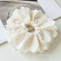 White lace scrunchie on a light surface with a magazine in the background