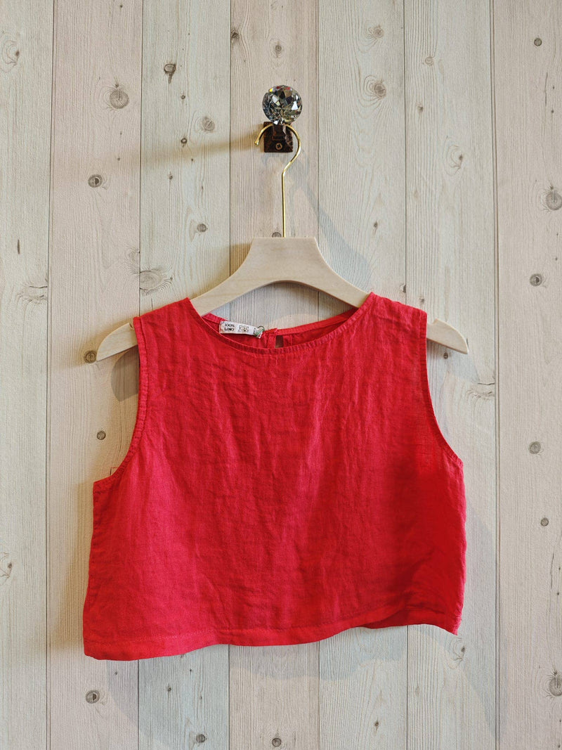 Red sleeveless top on a wooden hanger against a wooden wall.