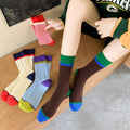 Colorful socks displayed on a wooden surface with a person wearing a green sports jersey.