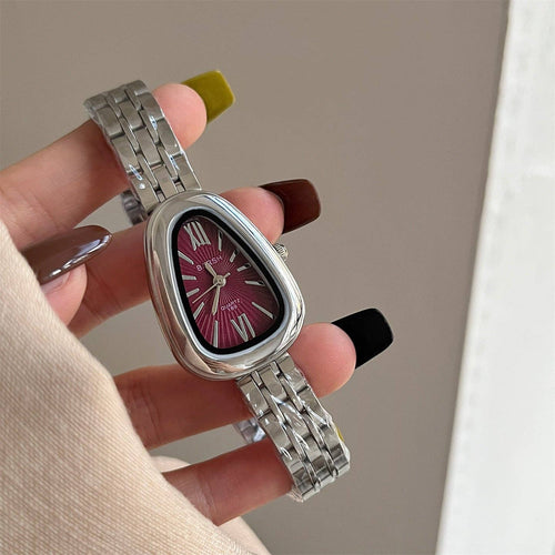 Silver watch with a pink face held by a hand against a neutral background