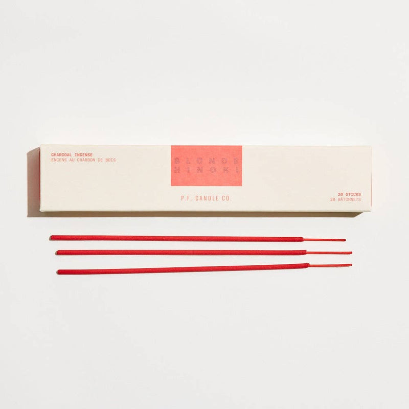Red incense sticks in front of a white box with 'P.F. Candle Co' branding on a light gray background