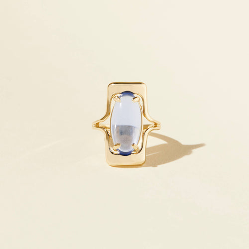 Gold ring with a central gemstone on a beige background