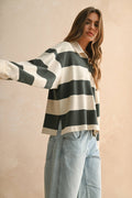 Woman wearing a black and white striped sweater with light blue jeans against a beige background