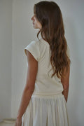 Woman wearing a white outfit against a plain background