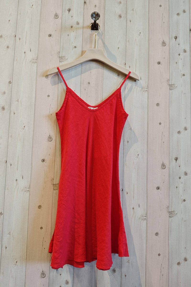 Red dress hanging on a wooden hanger against a wooden wall.