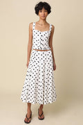 Woman wearing a polka dot dress against a beige background