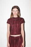 Woman wearing a maroon textured top and pants against a white background