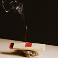 Incense stick with smoke rising from a box on a dark background