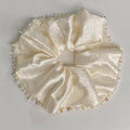 Cream-colored bow with pearl accents on a light gray background