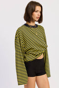 Woman wearing a yellow and black striped long-sleeve top and black shorts on a white background