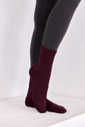 Burgundy socks worn with black tights on a white background