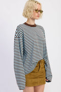 Person wearing a striped sweater and mustard skirt on a light background