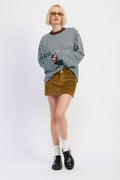 Person wearing a striped sweater, corduroy skirt, and black shoes on a white background