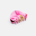 Pink hair clip with green accents on a white background