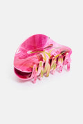Pink hair clip with multicolored teeth on a white background