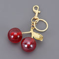 Keychain with red cherries and gold stem on a gray background