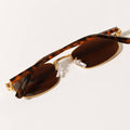 Sunglasses with tortoiseshell frame and brown lenses on a light background