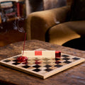 Checkered board with a red candle on a wooden table, blurred background