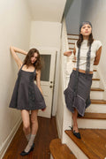 Two women standing in a home interior, one on the stairs and one by a door.