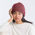 Person wearing a red knitted beanie against a white background