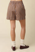 Striped shorts worn by a person on a beige background