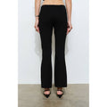 Person wearing black flared pants against a white background